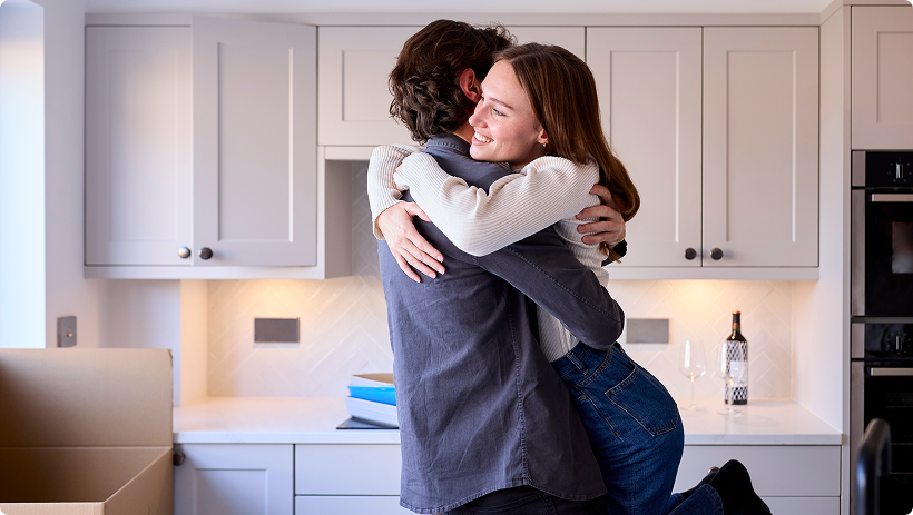 Couple hugging inside their new home, representing homeowners insurance.