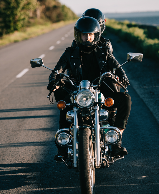 Happy couple riding a motorcycle on an open road, representing comprehensive motorcycle insurance and safe riding coverage.
