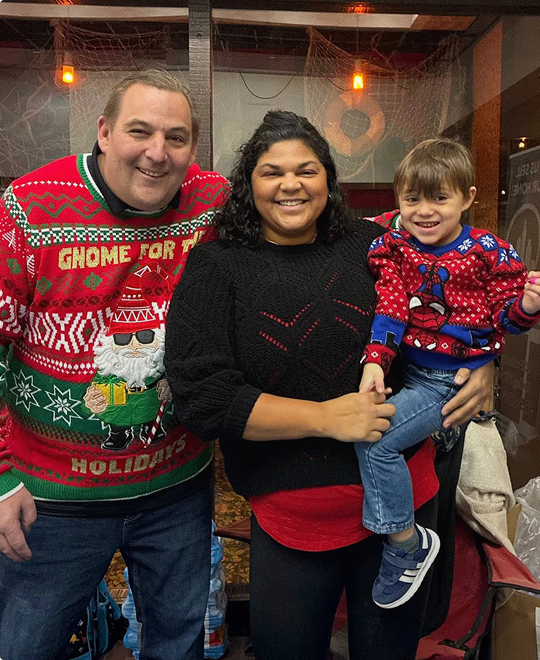 Happy family wearing festive Christmas sweaters, representing family life insurance.