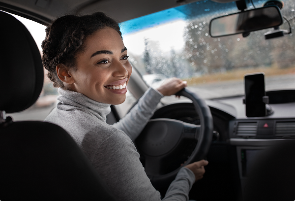 A happy woman driving her vehicle safely on the road, representing peace of mind and reliable auto coverage