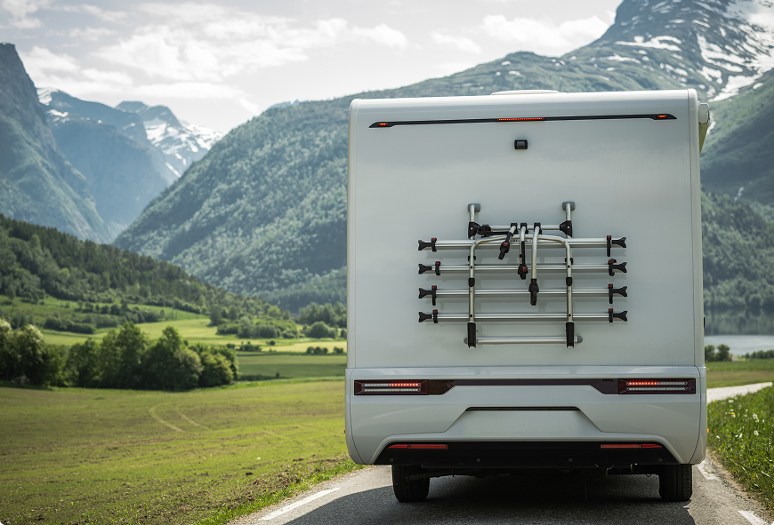Motorhome driving through a scenic mountain valley, representing comprehensive RV insurance for travel and road trips.