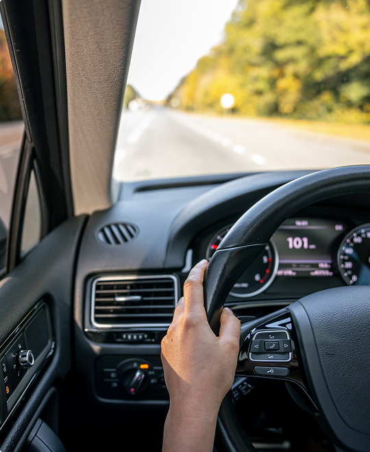 Person driving a car on an open highway, representing safe driving and Western NY auto insurance options.