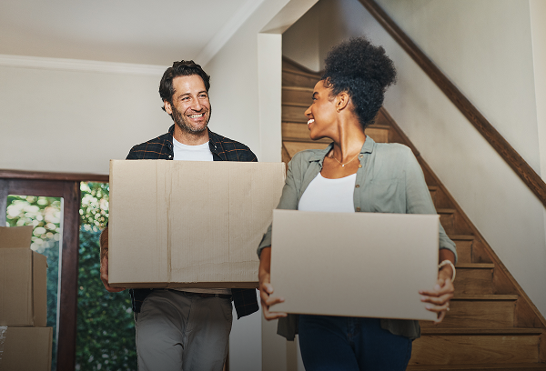 Happy couple laughing and celebrating while moving into their new home, holding a house key and looking at each other.