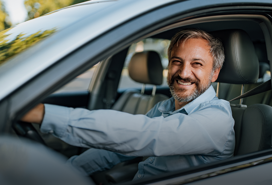 Smiling woman driving her car safely on the road, representing auto insurance protection.