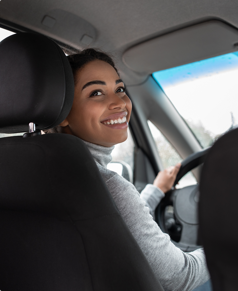 Smiling woman driving her car, representing auto insurance.